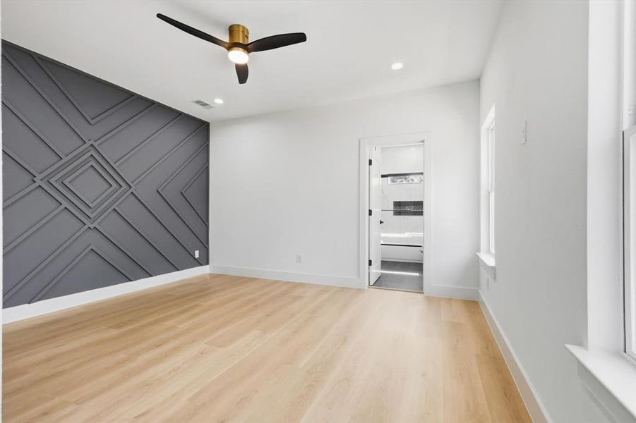 Empty room featuring an accent wall, a decorative wall, light wood-style flooring, a ceiling fan, and recessed lighting