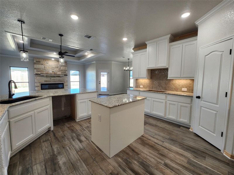 Kitchen featuring ornamental molding, white cabinets, a textured ceiling, ceiling fan, and decorative light fixtures