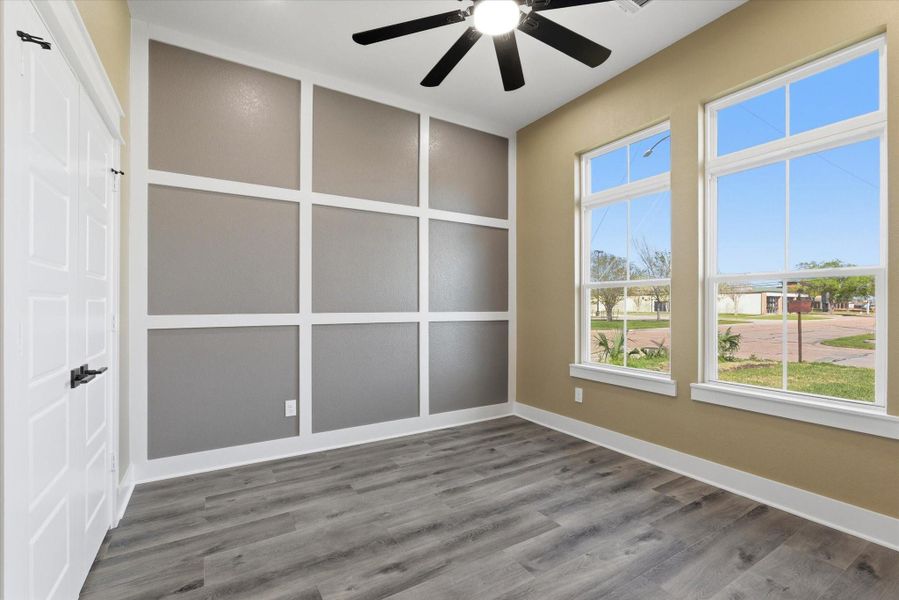 Bedroom/office showcases double glass doors, recessed lighting, a ceiling fan, a stylish accent wall, a spacious closet for ample storage, and two front-facing windows that fill the space with natural light.