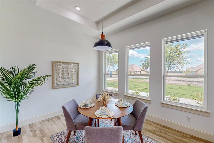 Dining area with light wood-type flooring and a tray ceiling