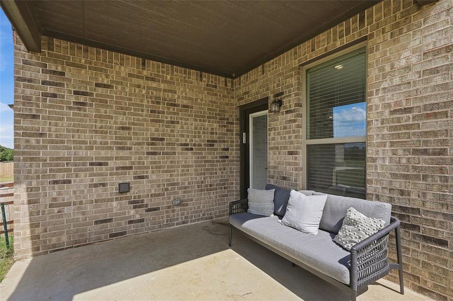 Covered patio featuring a concrete slab and a brick exterior wall