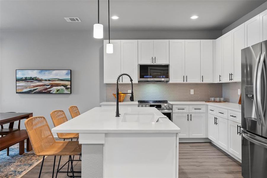 Kitchen with a kitchen island with sink, tasteful backsplash, and stainless steel appliances.