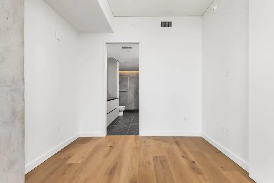 Naturally illuminated living space boasts warm hardwood flooring and leads to a chic, tiled bathroom.