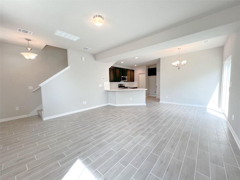 Unfurnished living room with wood finish floors, a chandelier, recessed lighting, and stairway
