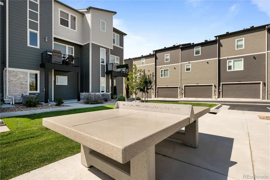 Community gathering area with outdoor ping pong table and landscaped courtyard space surrounded by townhomes.