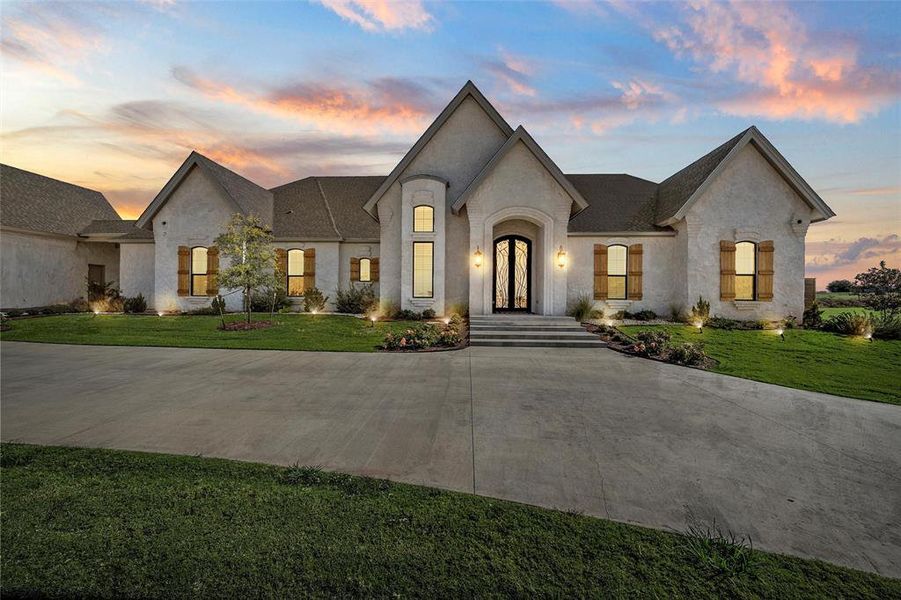 French country home featuring driveway, a front lawn, and roof with shingles