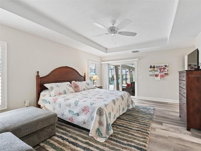 Primary Bedroom with Sliders leading out to the Lanai, Plantation Shutters, And coffered ceiling