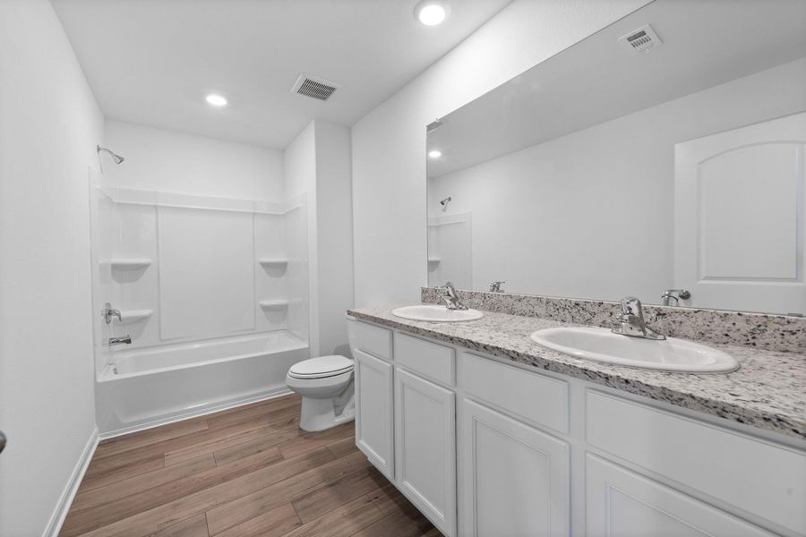Full bath featuring double vanity, shower / bathtub combination, and dark wood-style flooring