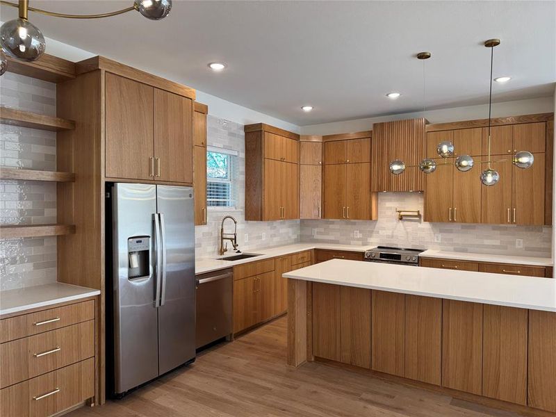 Kitchen with tasteful backsplash, sink, light hardwood / wood-style floors, and stainless steel appliances