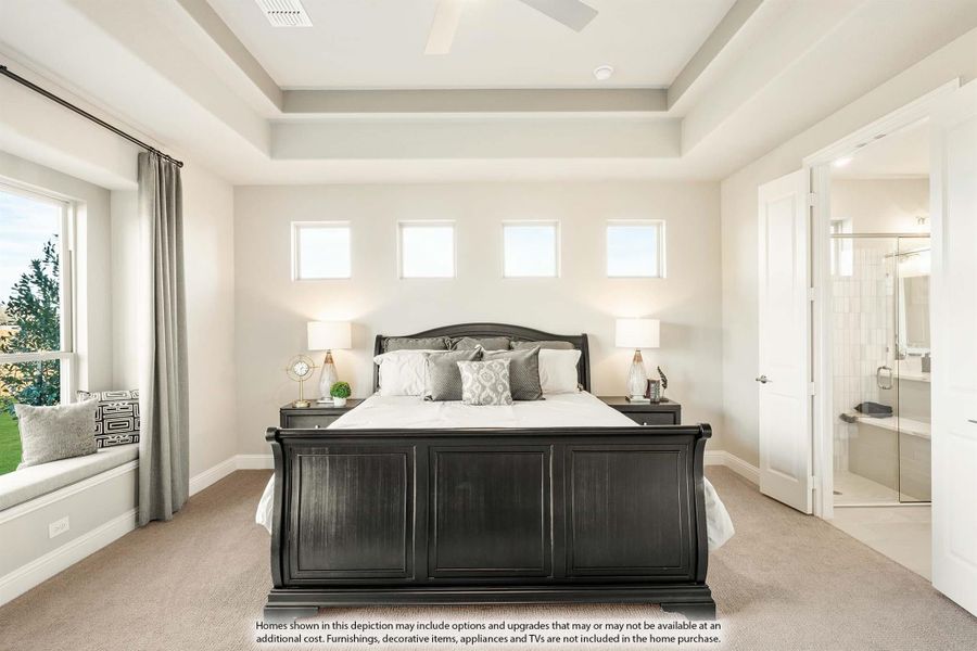 Master bedroom with tray ceiling, dark wood sleigh bed, window seat, and ensuite bathroom visible through open door