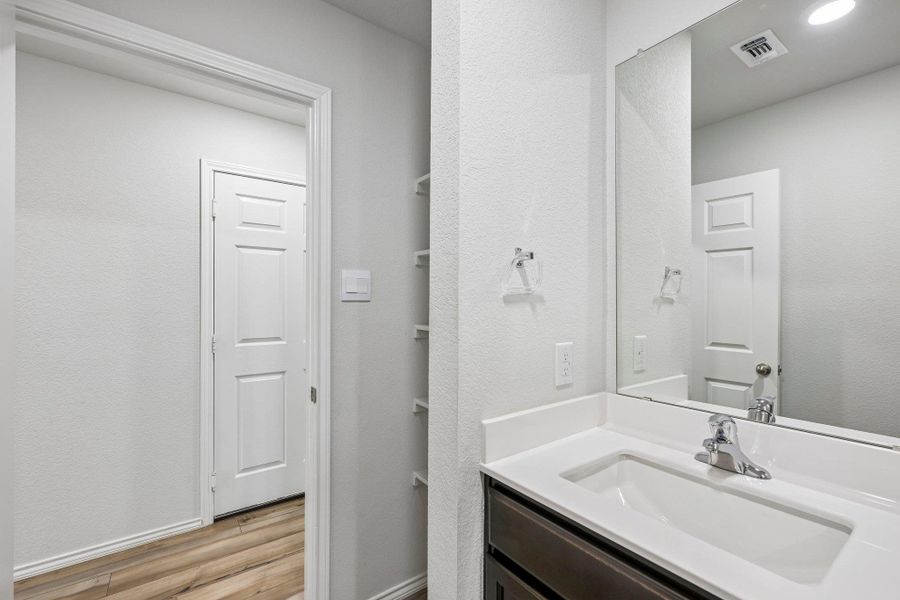 Bathroom vanity featuring a chrome faucet, integrated sink, and white countertop