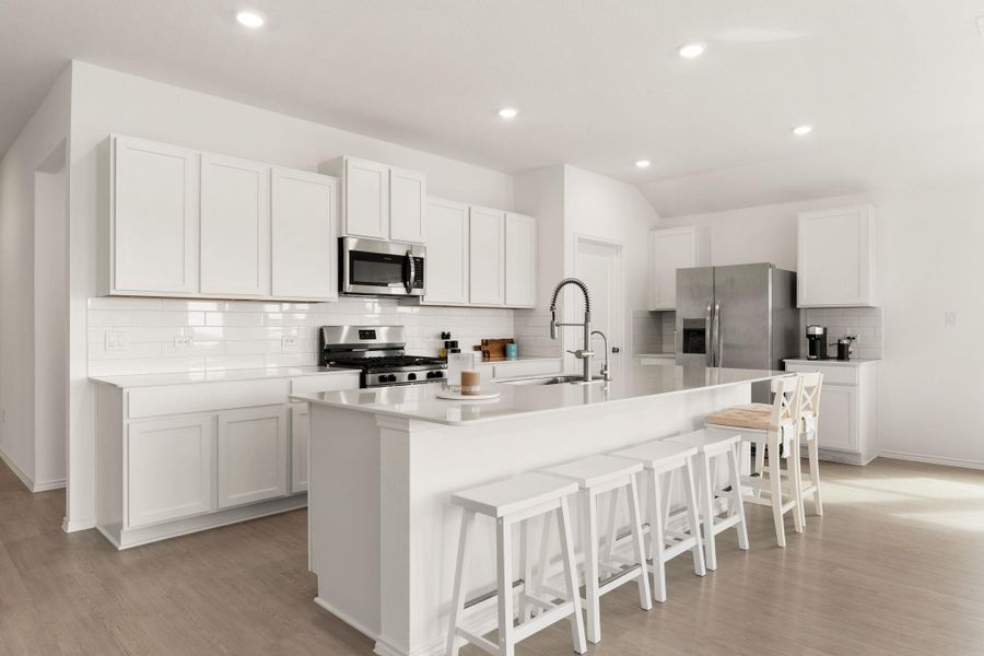 A pristine culinary space features sleek stainless steel appliances and an inviting kitchen island.