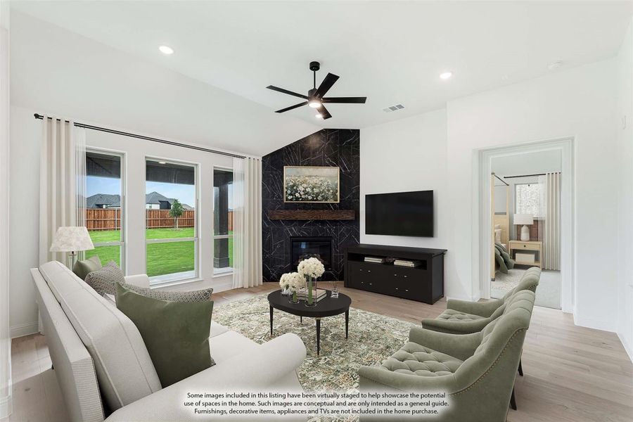 Living room with vaulted ceiling, black marble fireplace, ceiling fan, and large windows overlooking backyard