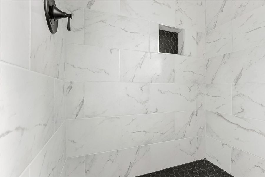 Luxurious ensuite shower with elegant marble tiles and sleek black fixtures for a modern touch.