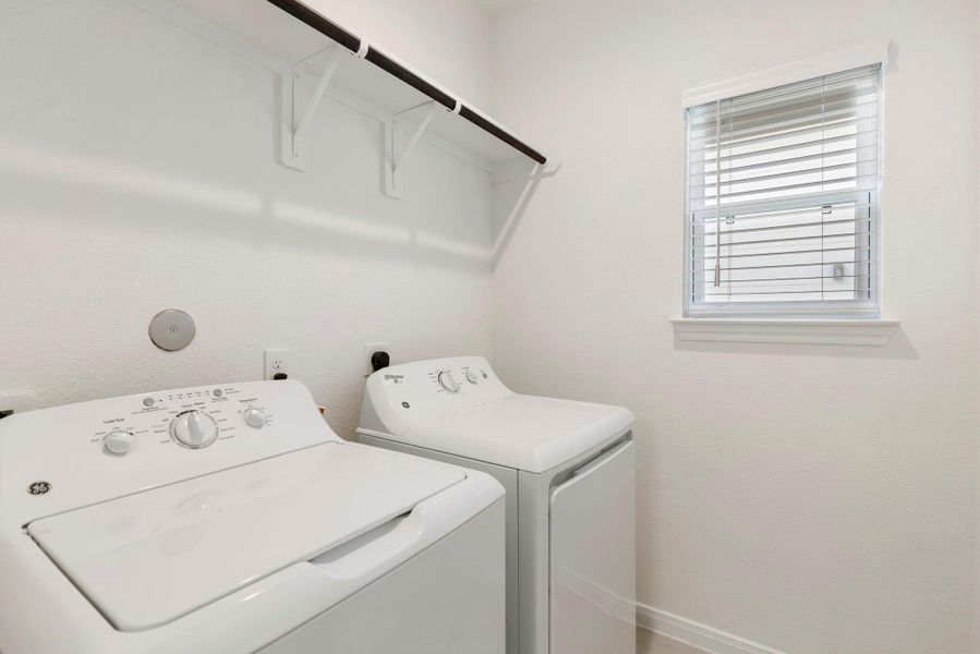 Enjoy a functional laundry space with an overhead shelf, clothing rod, and included washer and dryer.
