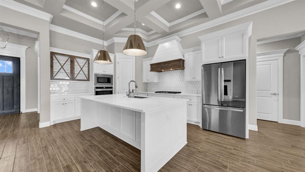 Kitchen with coffered ceiling, custom range hood, backsplash, and stainless steel appliances