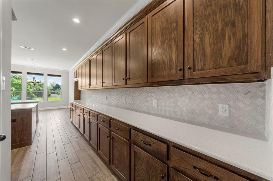 Kitchen featuring decorative backsplash, light countertops, baseboards, light wood-type flooring, and recessed lighting Kitchen featuring decorative backsplash, light countertops, baseboards, light wood-type flooring, and recessed lighting