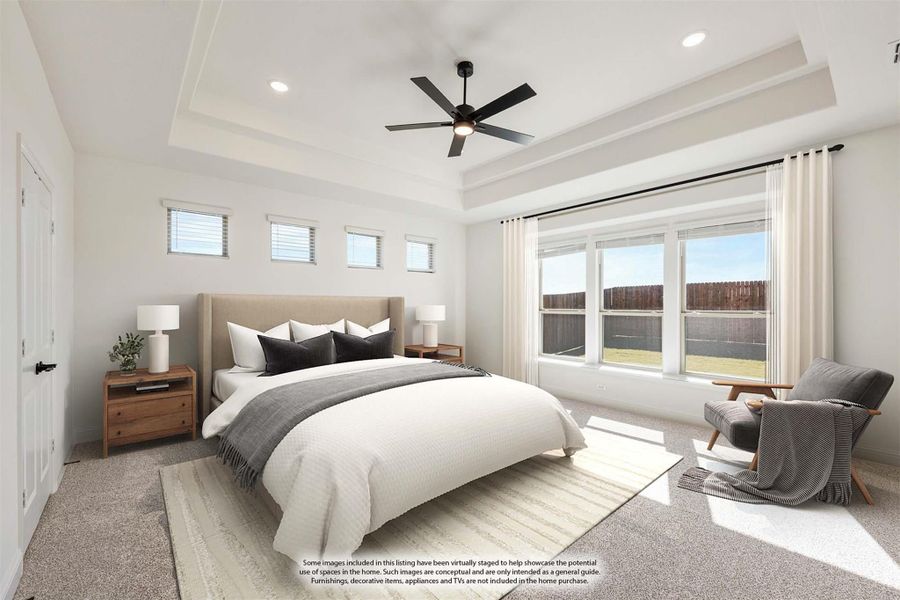 Spacious master bedroom with tray ceiling, ceiling fan, large windows, and carpet flooring Spacious master bedroom with tray ceiling, ceiling fan, large windows, and carpet flooring