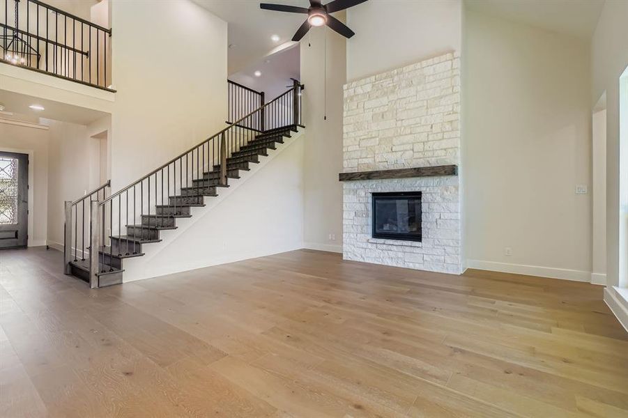 Unfurnished living room featuring high vaulted ceiling, stairs, wood finished floors, a ceiling fan, and recessed lighting
