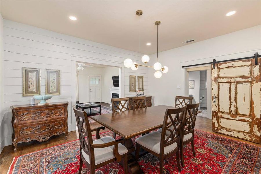 Dining area featuring hardwood flooring, shiplap accent wall, recessed lighting, and a modern chandelier
