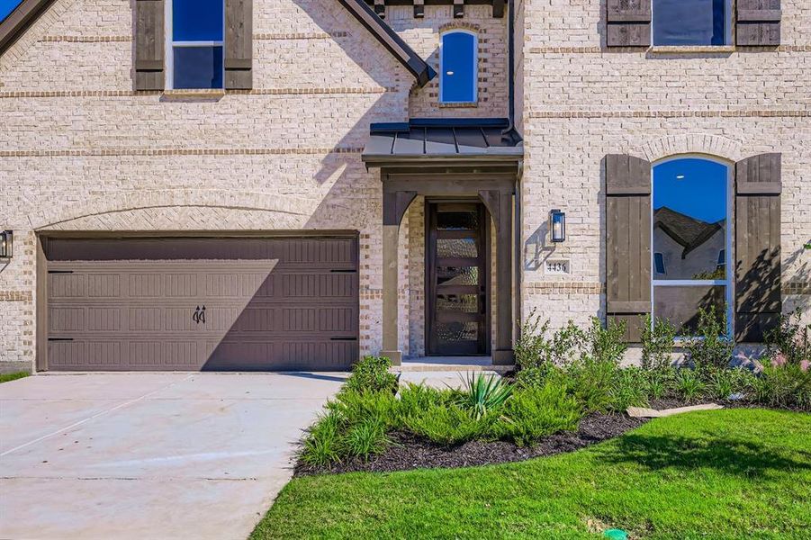 Property entrance featuring brick siding, concrete driveway, a standing seam roof, and a metal roof