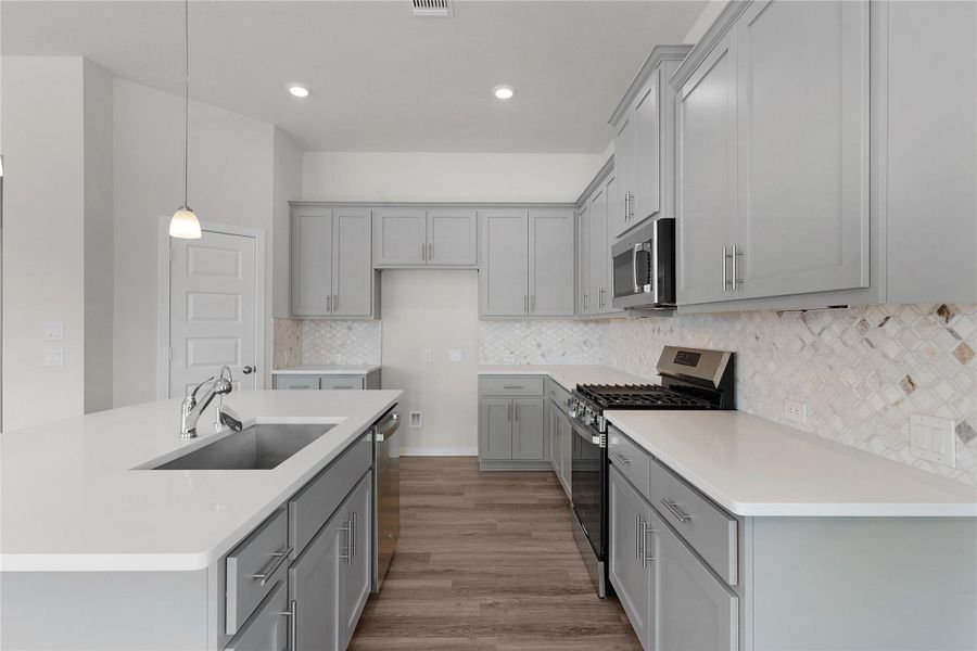 Kitchen with stainless steel appliances, a kitchen island with sink, gray cabinetry, and light wood-type flooring