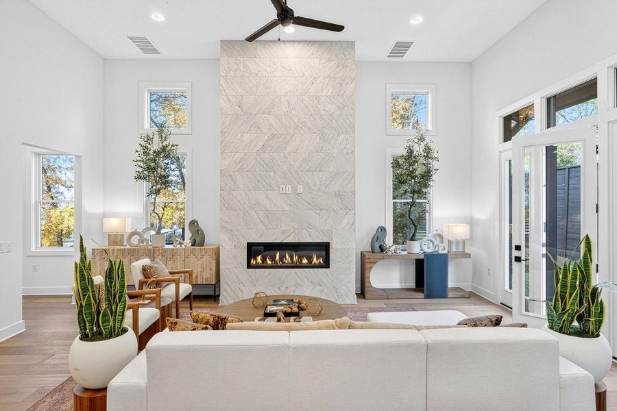 Living area with a towering ceiling, a fireplace, wood finished floors, a ceiling fan, and recessed lighting