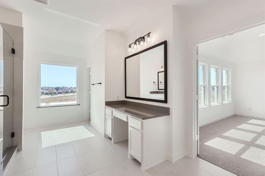 Bathroom featuring vanity, a wealth of natural light, tile patterned flooring, and an enclosed shower