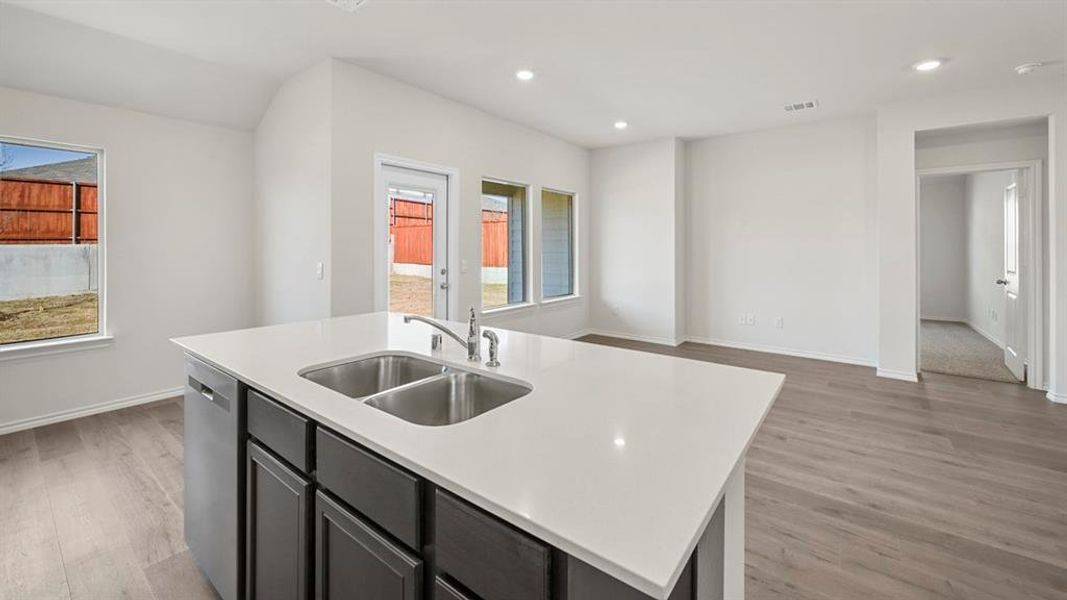 Kitchen featuring light wood-style flooring, a center island with sink, recessed lighting, stainless steel dishwasher, and light stone countertops