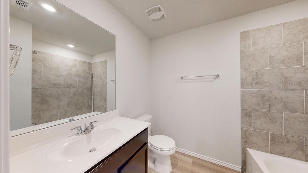 Bathroom featuring a single vanity with a white countertop, an undermount sink, and dark wood-finish cabinetry