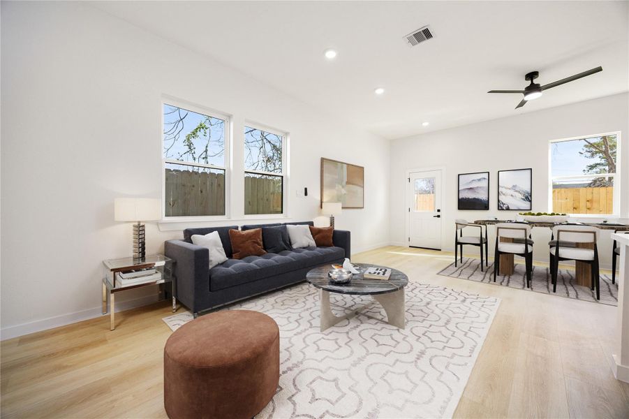 Bright and inviting living area featuring high ceilings, recessed lighting, and wood-look flooring. Large windows provide abundant natural light, while the open layout offers easy flow into the dining area, ideal for both everyday living and entertaining. *Virtually Staged Bright and inviting living area featuring high ceilings, recessed lighting, and wood-look flooring. Large windows provide abundant natural light, while the open layout offers easy flow into the dining area, ideal for both everyday living and entertaining. *Virtually Staged