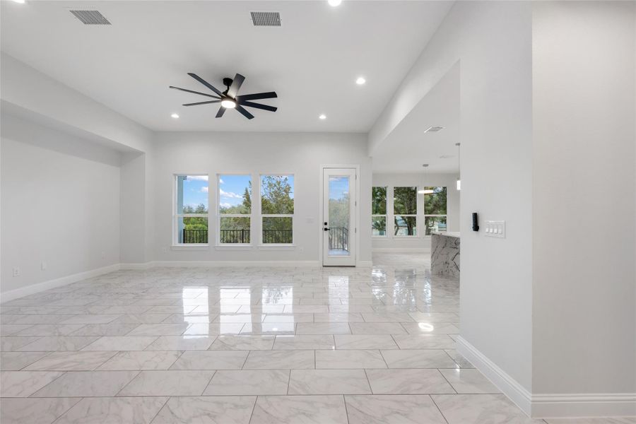 Unfurnished living room featuring a ceiling fan, light marble finish floors, and recessed lighting