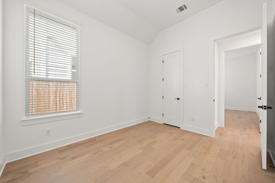 Unfurnished bedroom with vaulted ceiling and light wood finished floors