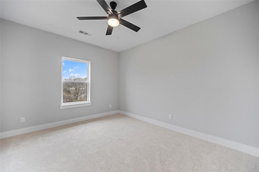 Unfurnished room with visible vents, light carpet, baseboards, and ceiling fan