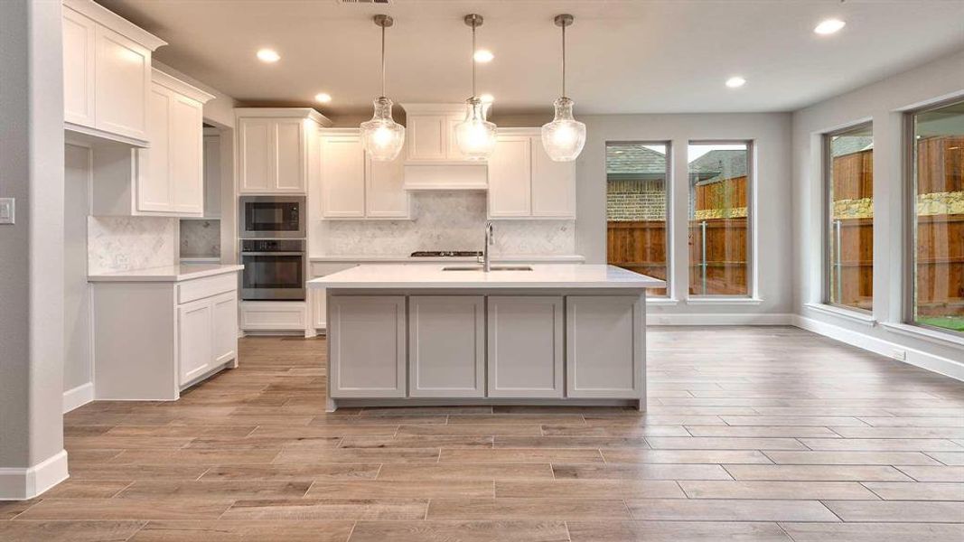 Kitchen with stainless steel appliances, hanging light fixtures, and white cabinets