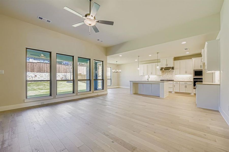 Unfurnished living room with a chandelier, recessed lighting, light wood finished floors, and a ceiling fan