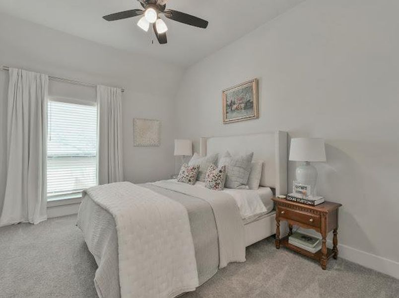 Carpeted bedroom featuring a ceiling fan and vaulted ceiling Carpeted bedroom featuring a ceiling fan and vaulted ceiling