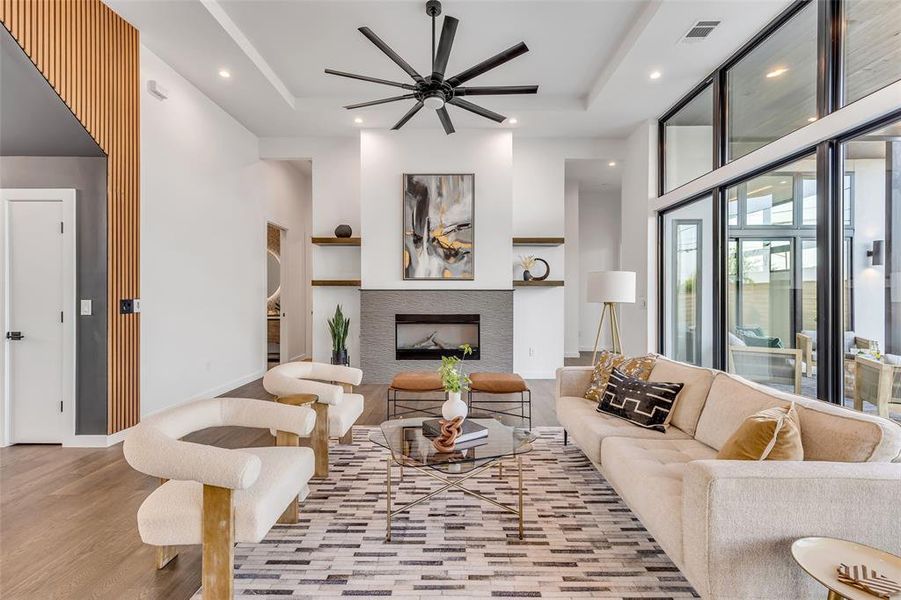 Step into sophistication in this sunlit living room, featuring soaring ceilings and a sleek fireplace, perfect for stylish entertaining.