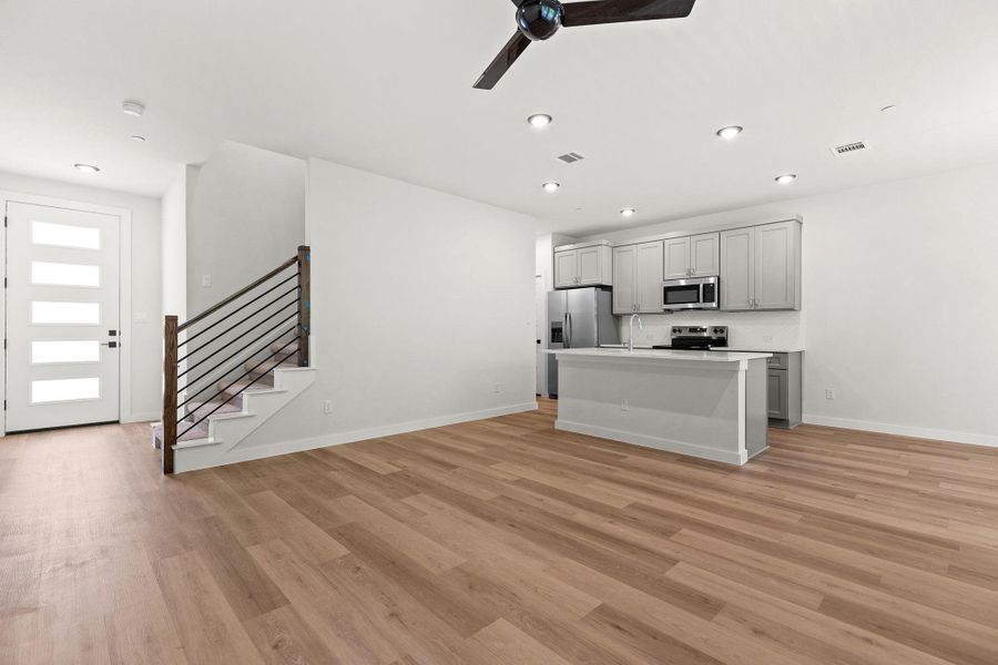 A contemporary open-concept layout features rich hardwood flooring and a functional kitchen island. A contemporary open-concept layout features rich hardwood flooring and a functional kitchen island.