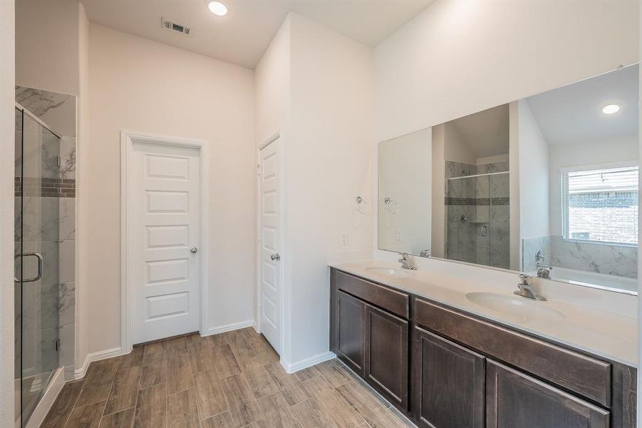 Full bathroom with a shower stall, double vanity, recessed lighting, wood tiled floors, and a garden tub Full bathroom with a shower stall, double vanity, recessed lighting, wood tiled floors, and a garden tub