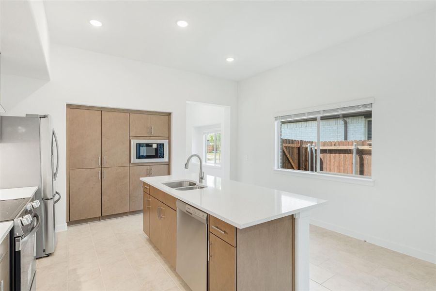 Kitchen with center island, sink, wood cabinets, built-in microwave, and stainless steel appliances on tile floors