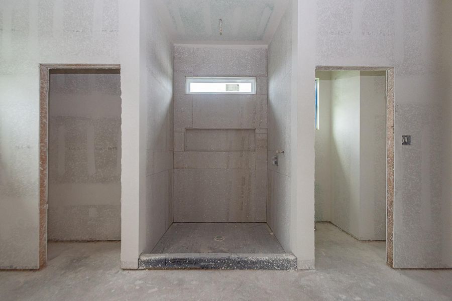 Spacious unfinished bathroom with a walk-in shower featuring a tall niche and a sleek horizontal window for natural light. Spacious unfinished bathroom with a walk-in shower featuring a tall niche and a sleek horizontal window for natural light.