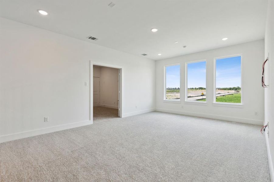Room featuring three large windows with white trim, recessed lighting, and light-colored carpeting Room featuring three large windows with white trim, recessed lighting, and light-colored carpeting