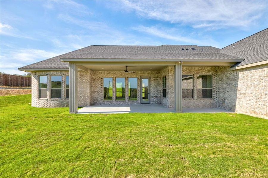 Rear view of house with a lawn, ceiling fan, and a patio area