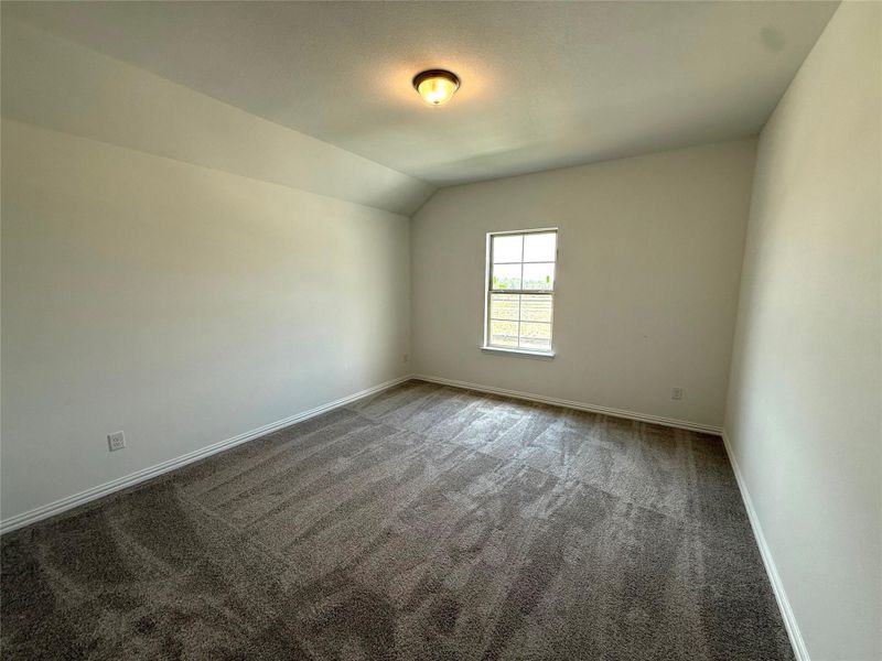 Empty room with carpet and lofted ceiling Empty room with carpet and lofted ceiling