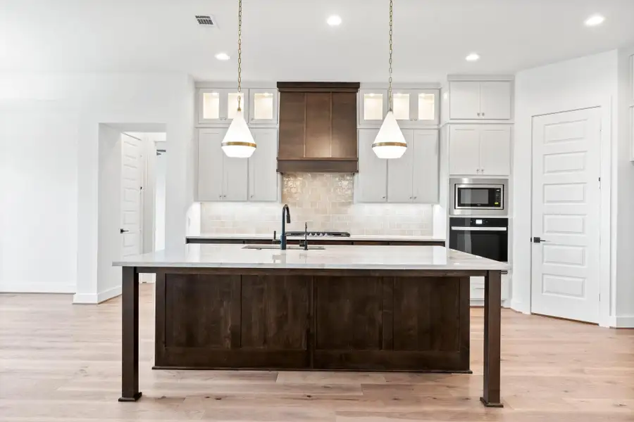 Kitchen with Cabinets to the Ceiling, Custom Hood with Vent to Exterior, and Stylish Lighting.