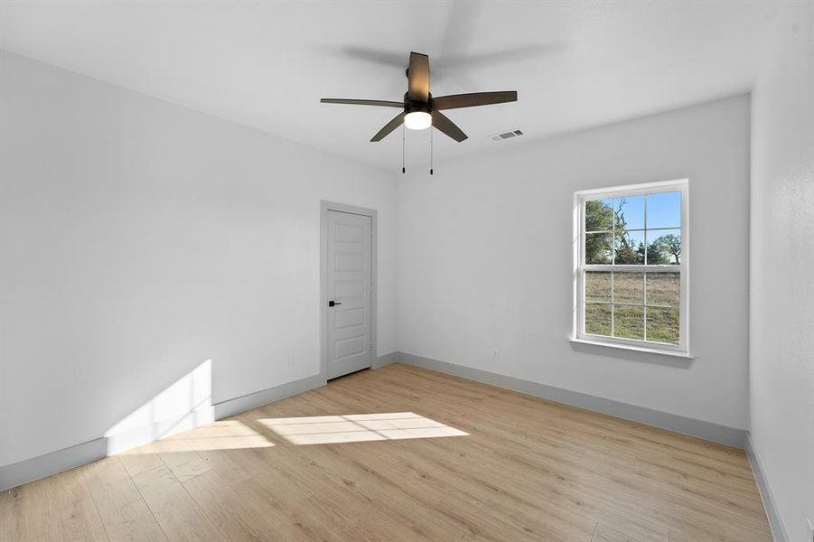 Spare room with light wood finished floors and ceiling fan