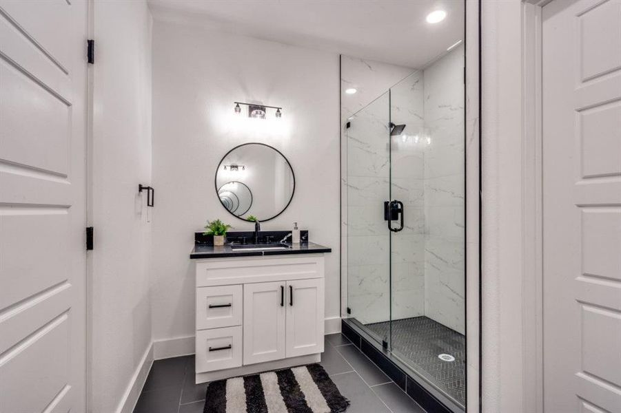 Bathroom featuring a marble finish shower, vanity, tile patterned floors, and recessed lighting