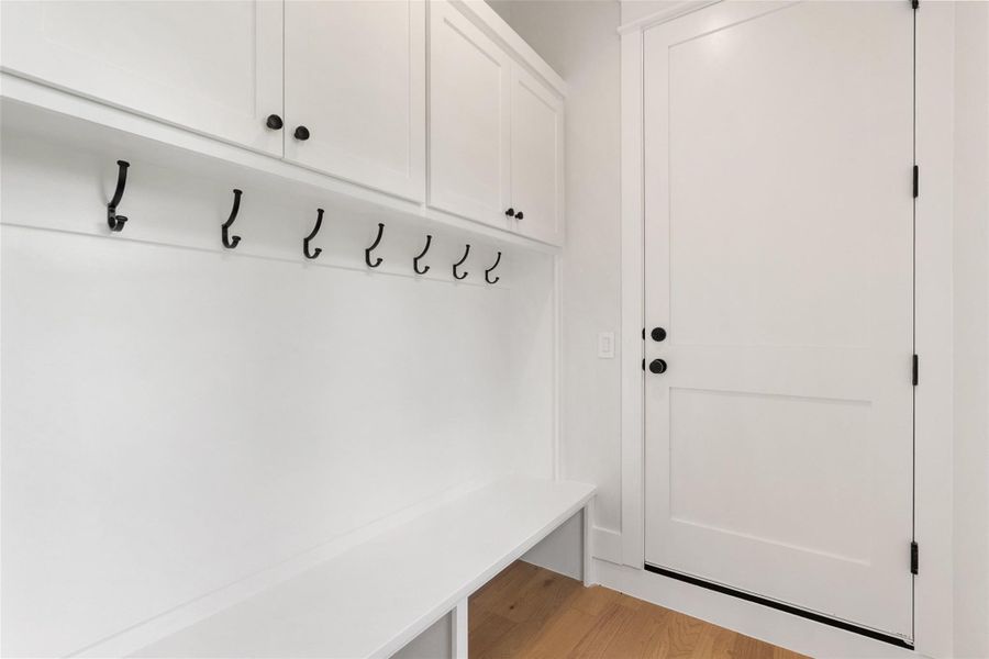 A well-appointed mudroom offers functional storage with upper cabinetry and practical coat hooks.