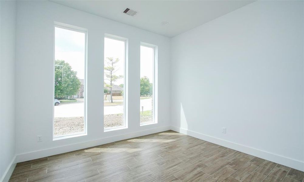 Great study featuring floor-to-ceiling windows that let in plenty of natural light, complemented by fresh, neutral walls and stylish wood flooring.